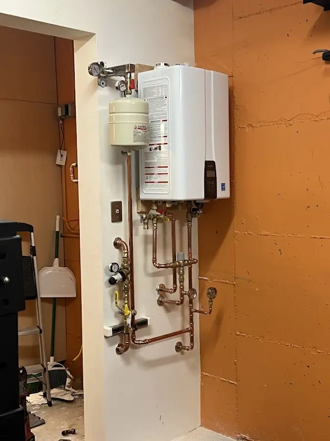 Plumbing technician inspecting water heater connections in Paola